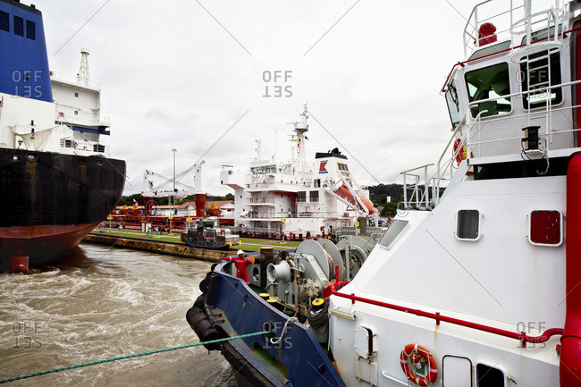 Crew member gives directions to the wheel house of a tugboat while transiting the Miraflores Locks of the Panama Canal