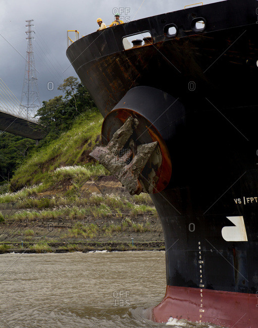 Crew members from a cargo ship look down while being assisted by a tugboat on the Panama Canal