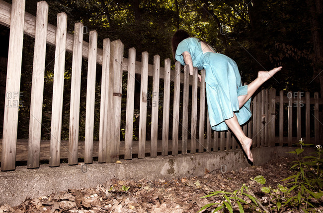 Woman climbing over a fence