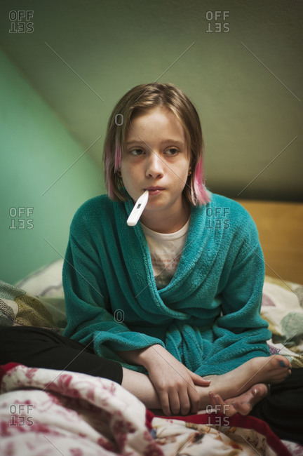 Girl checking her fever with a thermometer