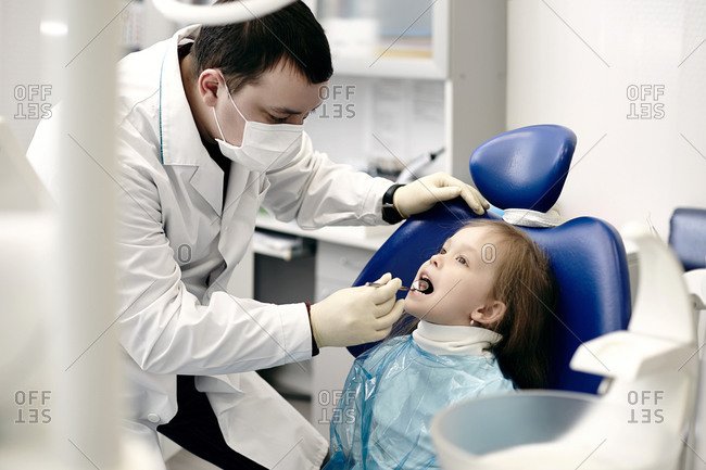 Caucasian dentist examining girl\'s teeth