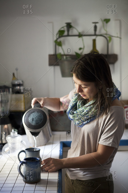 Woman pouring hot water into mugs