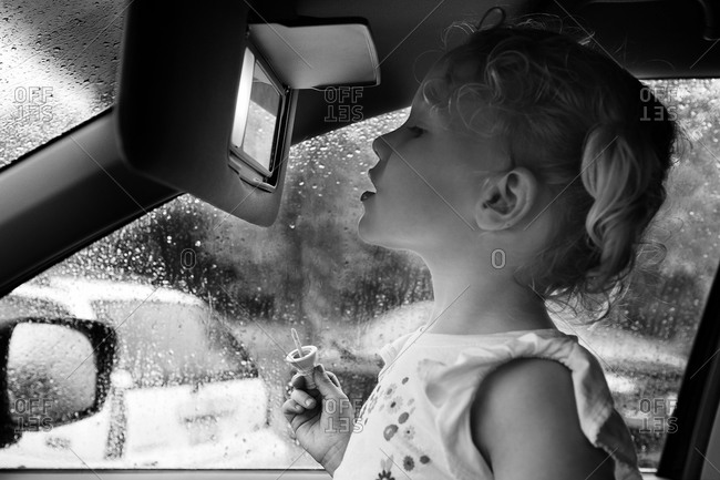 Little girl applying a lip gloss in the car