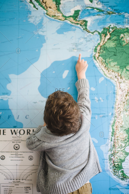 Young boy stretches to point to a place on a large map
