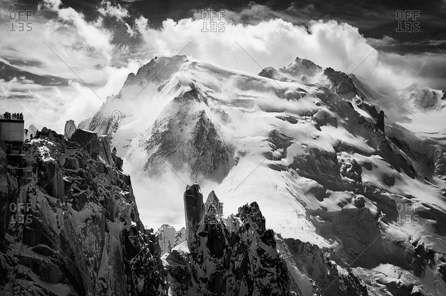 A climber finishes the Arete des Cosmiques on the Aiguille du Midi cablecar station, with the north face of Mont Blanc du Tacul in the background, Chamonix, France
