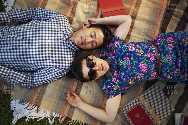 Couple lying head to head on picnic blanket