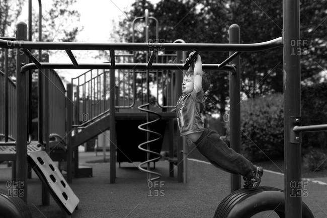 Boy hanging on a jungle gym at a playground