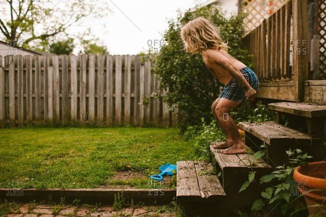 Young child prepares to jump off wooden steps