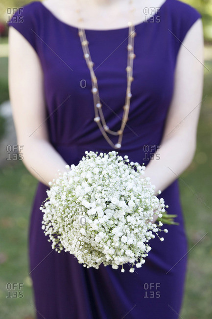 Mid section view of bridesmaid holding a white bouquet