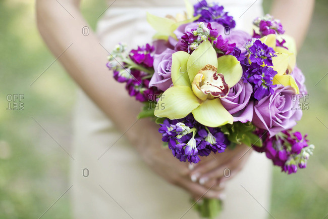 Mid section view of bride holding purple and green bridal bouquet