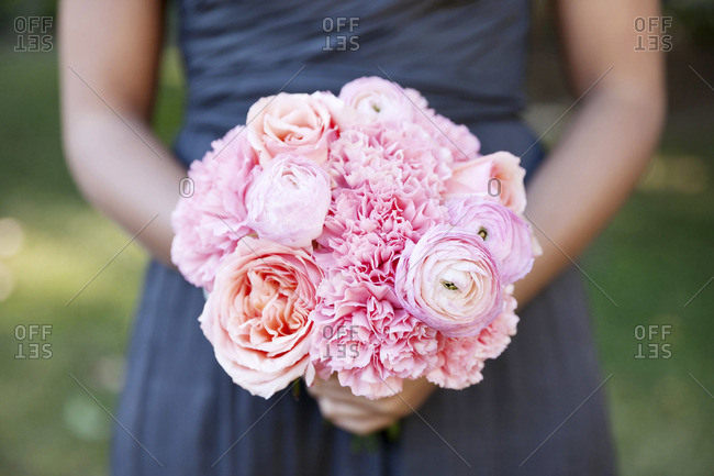 Mid section view of bridesmaid holding a pink variation bouquet