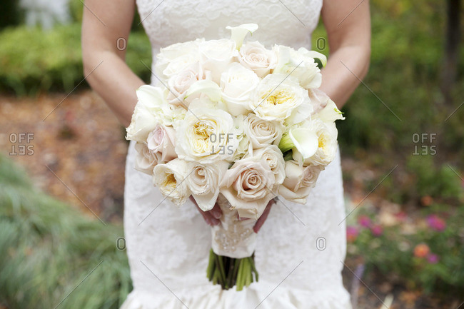 Mid section view of bride holding pale pink and white bridal bouquet
