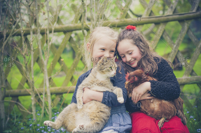 Portrait of two little girls with cat and chicken