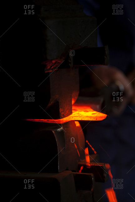 Blacksmith working on glowing axe at historic blacksmith\'s shop, Josefsthal, Bavaria, Germany