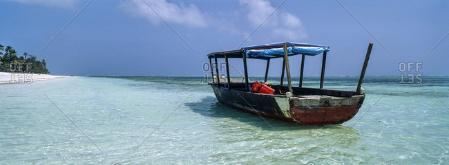 A fishing boat moored beside a stretch of deserted tropical beach