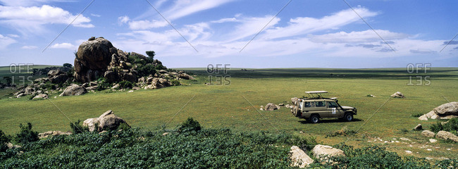 A safari beside rocky granite outcrop known as a kopje on a short grass savannah plain