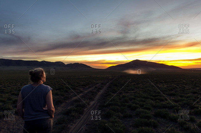 A tourist on an African safari watches a blazing sunset over distant mountains