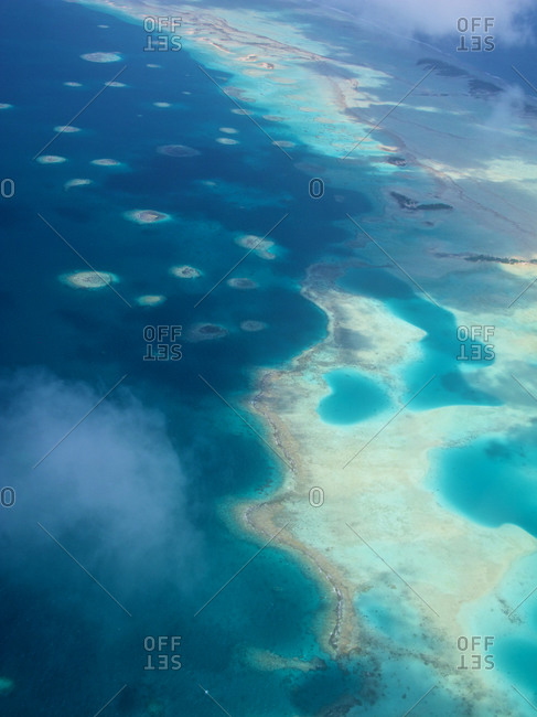 Holes in the reef and coral heads dotting the lagoon can be seen beneath the clouds in Kaukura atoll.