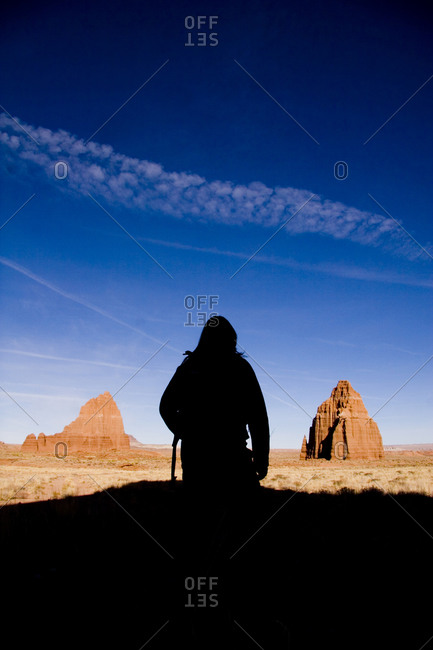 A woman stands in silhouette admiring the Temple of the Sun and Moon.