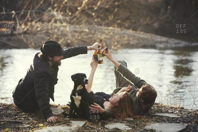 Friends toasting with beer bottles on a riverbank