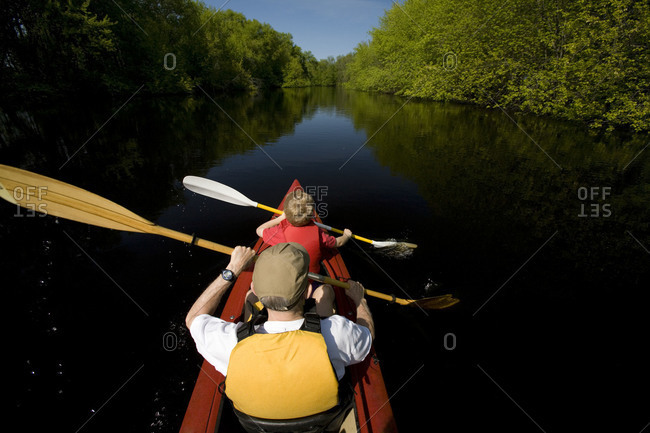 Father and son kayaking in river.