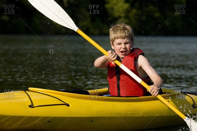 A boy kayaking on pond.