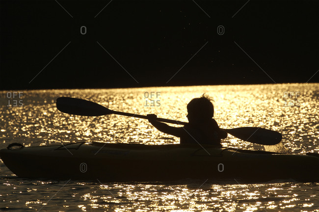 Boy kayaking in the sunset on Walden Pond