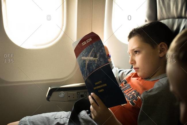 Boy reading the safety information on an airplane