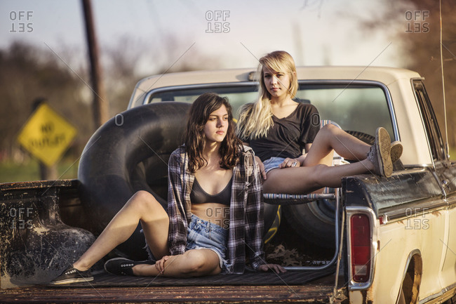 Two girls posing in a back of a pick up truck
