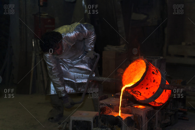 Foundry worker pouring hot metal into cast, Munich, Germany