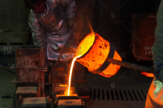 Foundry worker pouring hot metal into cast, Munich, Germany