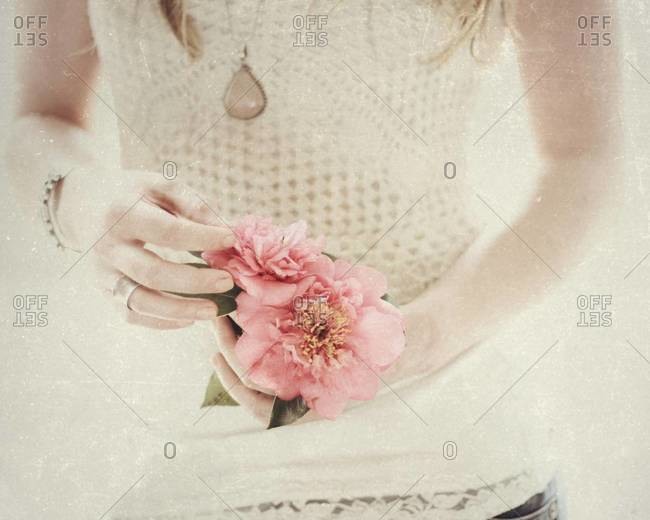 Mid section view of a woman holding pink flower
