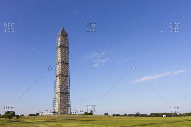 A view of the Washington Monument with the the moon still visible in the morning sky.