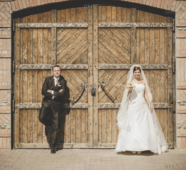 Newlywed couple posing at a wooden entrance