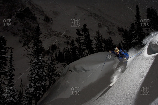 A male skier makes a powder turn at night in the Tobacco Root Mountains near Pony, Montana