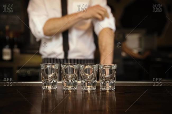 Bartender rolling up sleeves behind bar, Williamsburg, Brooklyn