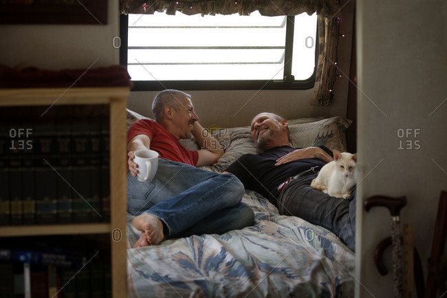 Same-sex couple chilling out on the bed in a camper trailer