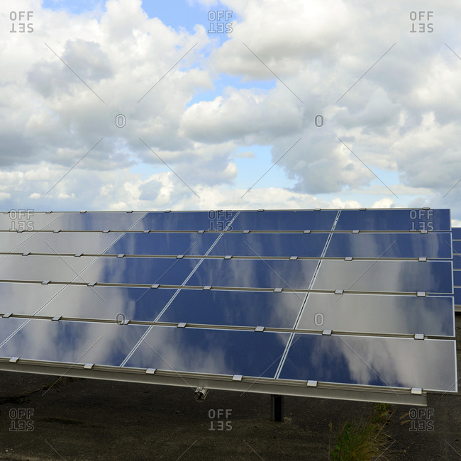 Photoelectric cells of solar power plant with reflections of clouds