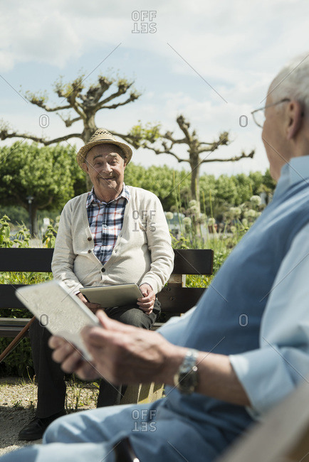 Two old men using tablet computers in the park