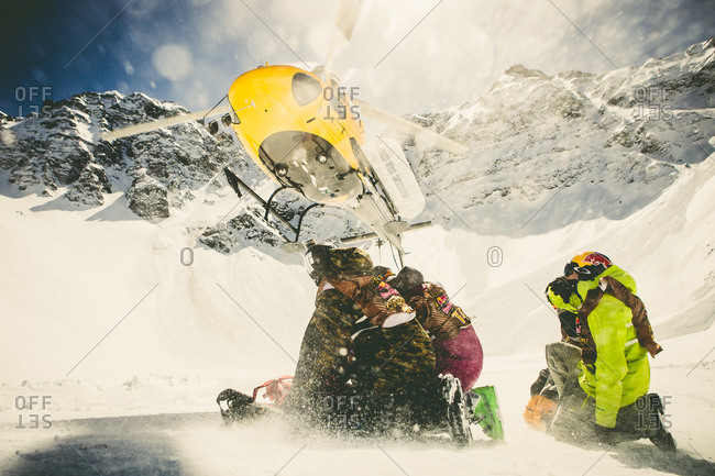 Skiers wait to board a helicopter in the mountains.