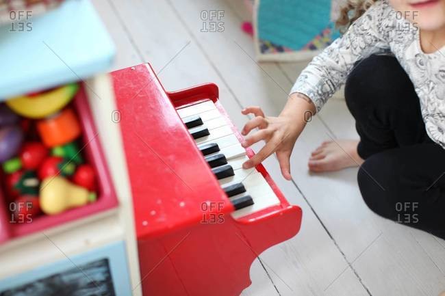 Girl\'s hand playing toy piano at playroom