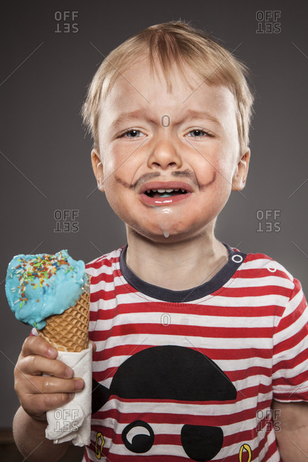 Portrait of crying looking little boy with painted beard and ice cream