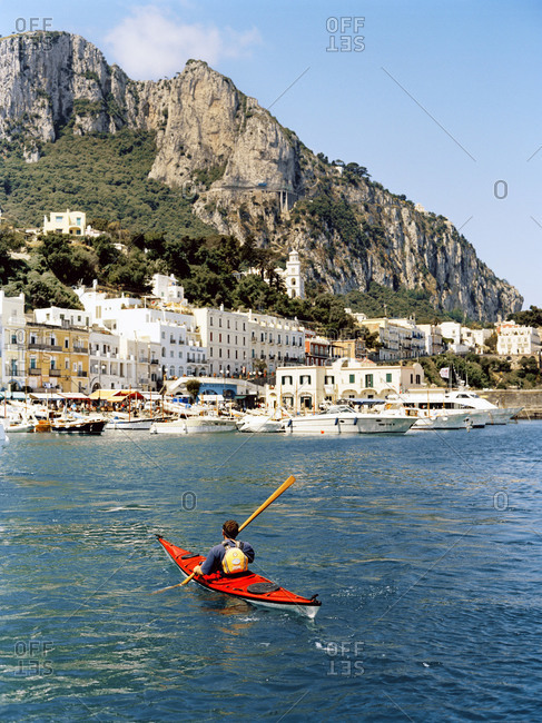 Man in a kayak rowing to Capri Harbor, Italy