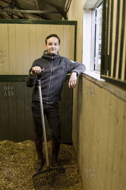 Portrait of confident young man with pitchfork in horse stable