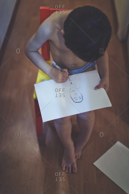 Boy drawing a face on a paper
