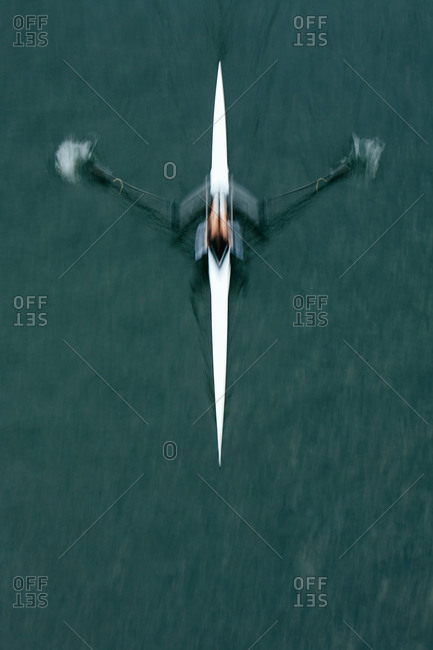 Person rowing crew boat, overhead view, blurred motion