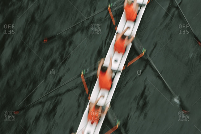 Group of rowers racing crew boat, blurred motion