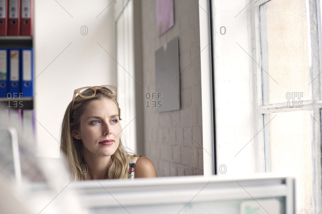 Blonde woman staring out of an office window