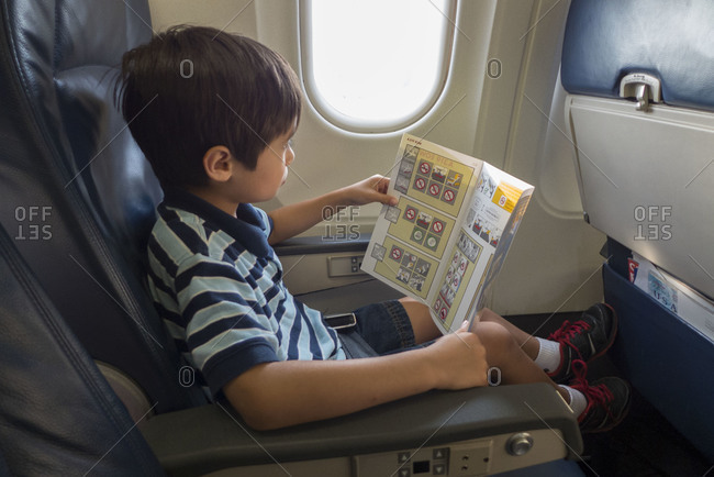 A young boy reads the safety card on an airplane flight