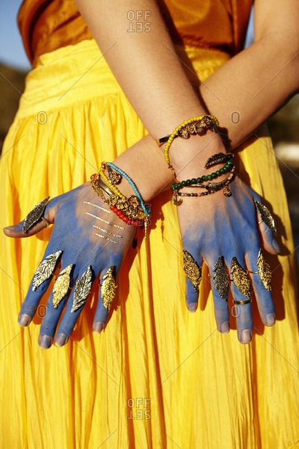 Mid section view of a woman showing her painted hands and golden rings